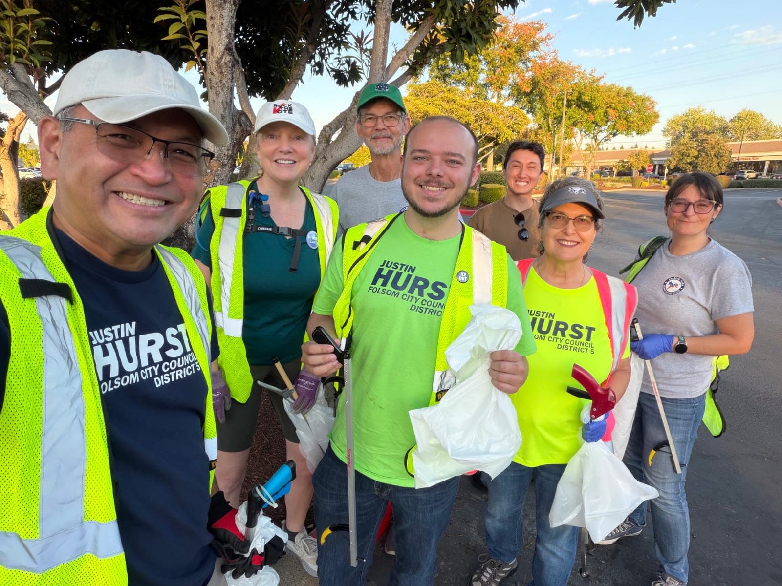 Justin and a group of volunteers in safety vests holding trash bags and grabbers