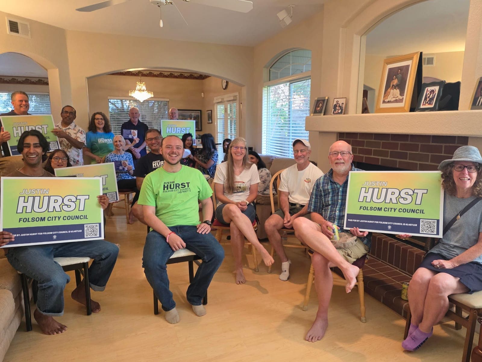 Justin seated among a living room full of supporters holding Hurst yard signs