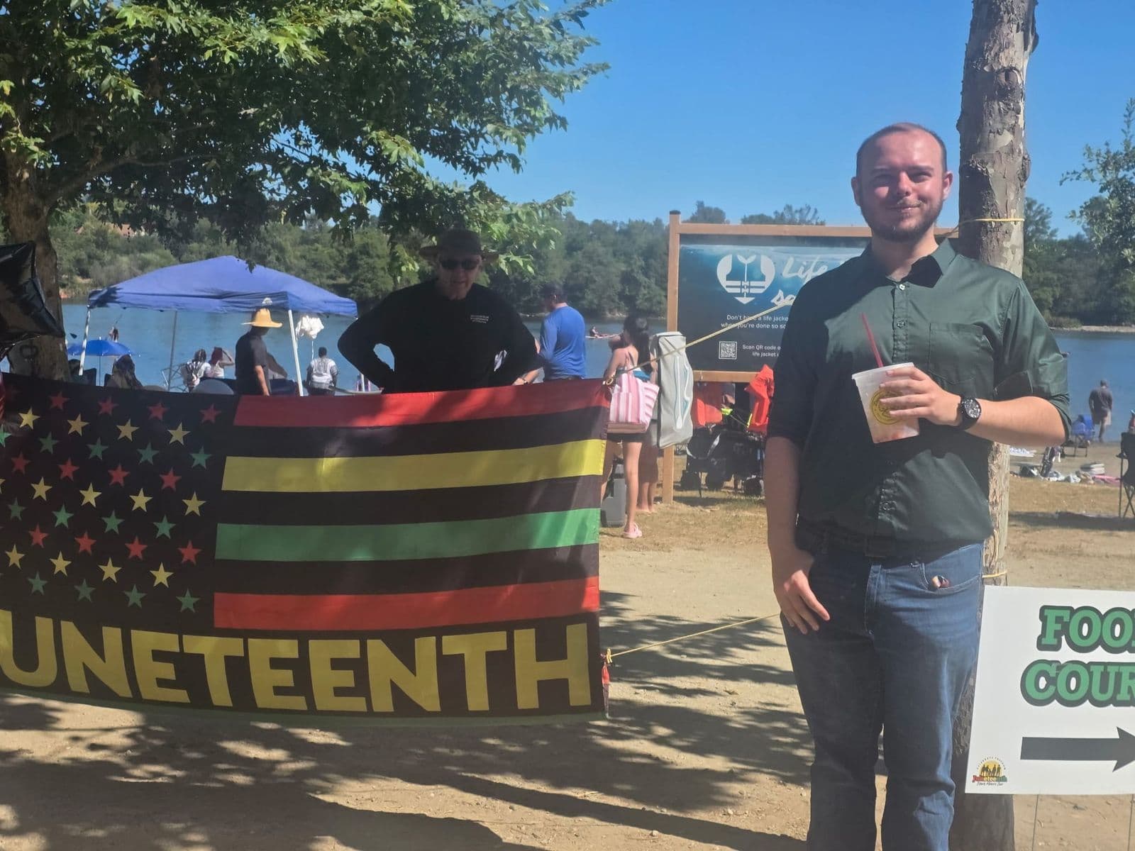 Justin standing beside a Juneteenth banner at an outdoor celebration