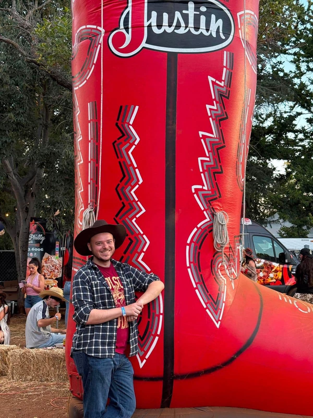 Justin in a cowboy hat beside a giant inflatable boot that reads Justin